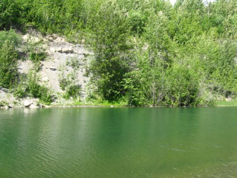 1978 Ford Bronco - A tranquil quarry lake reflects the lush greenery of the surrounding cliffside on a sunny day.
