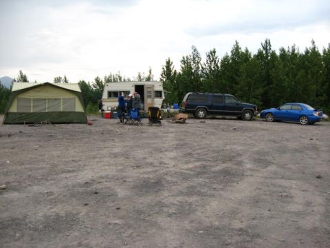 1978 Ford Bronco - A campsite scene with a tent, trailer, and two vehicles under a cloudy sky.