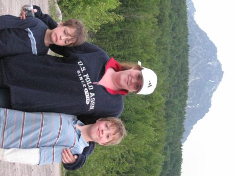 1978 Ford Bronco - A group of three people, two boys and an adult, are photographed outdoors with a lush green forest and a distant mountain range.