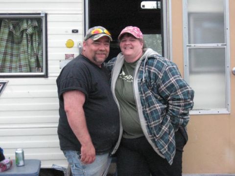1978 Ford Bronco - A couple poses for a photo in front of a trailer, with a can of soda on a table nearby.