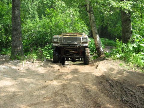 1978 Ford Bronco - A lifted 1978 Ford Bronco with off-road tires is seen from the front in a wooded area.