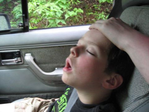 1978 Ford Bronco - A child sleeps soundly in the backseat of a vehicle, with a hand gently resting on their forehead.