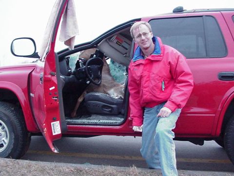 1991 Ford Bronco - A man poses next to his red SUV, which has a deer carcass loaded into the passenger seat.