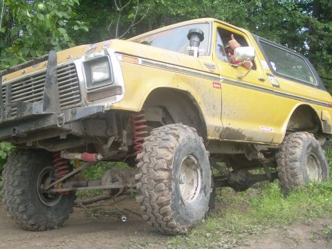 1978 Ford Bronco - A yellow 1978 Ford Bronco is shown with a lifted suspension and large off-road tires, giving a thumbs-up from the driver's seat.