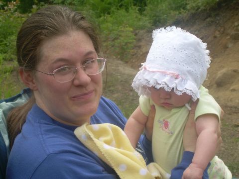 1978 Ford Bronco - A woman holds a baby dressed in a bonnet and light green onesie while outdoors.