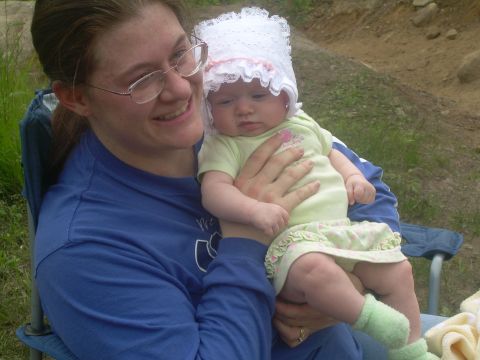 1978 Ford Bronco - A woman smiles while holding a baby dressed in a bonnet and light green outfit.
