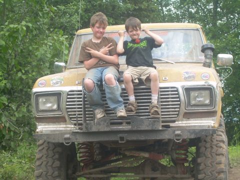 1978 Ford Bronco - Two boys pose on the front of a modified yellow Ford truck with large off-road tires and a snorkel.