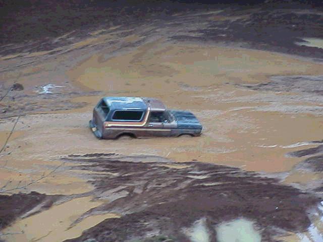 SUV stuck partway submerged in a wide expanse of brown muddy water