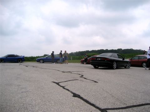 1993 Ford Probe - A black 1993 Ford Probe is seen from the rear, parked alongside other vehicles at an outdoor gathering.
