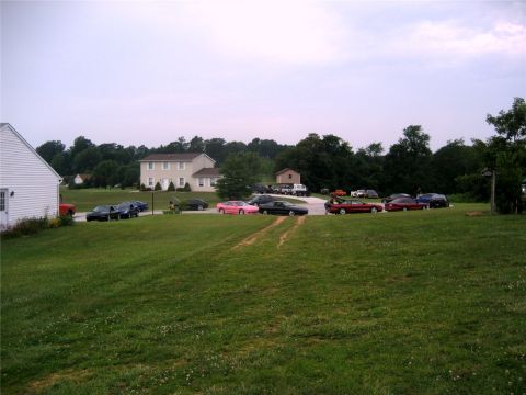 1993 Ford Probe - A collection of cars are parked on a grassy area in front of a large house and trees. Several coupes and sedans are visible, including a pi…