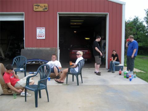 1993 Ford Probe - A group of people are gathered outside a red garage with the doors open, with a red Ford Probe visible inside. One person is sitting in a c…
