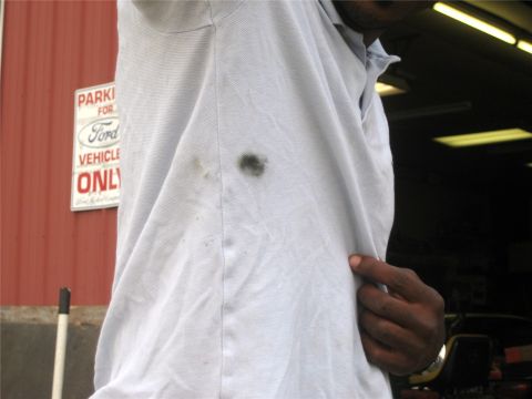 1993 Ford Probe - A person's light blue polo shirt has a dark stain on it. A red metal wall with a "PARKING FOR FORD VEHICLE ONLY" sign is visible in the bac…