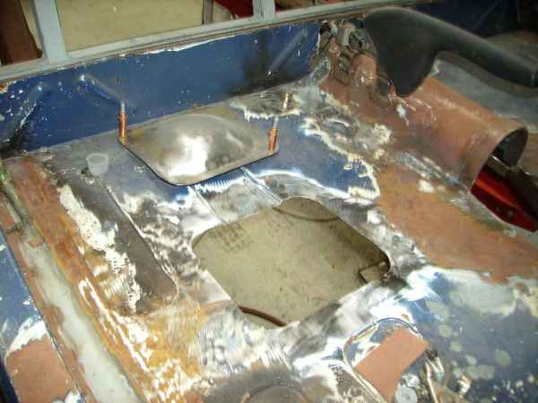 Welded bare-metal patch panels and cut-out in a stripped car bulkhead during fabrication
