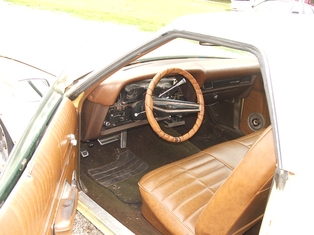 Tan vintage car interior with steering wheel, bench seat and dashboard
