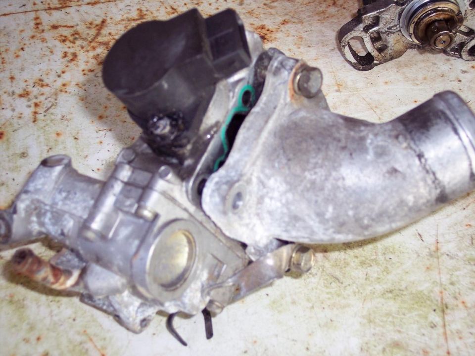 Used automotive part, possibly throttle body, with black plastic component.