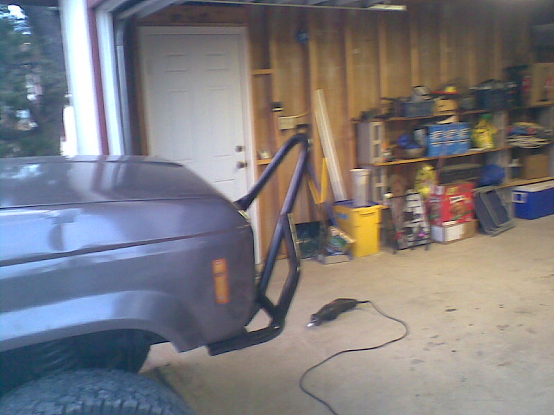 Dark gray SUV fender with custom black brush guard being installed, garage setting.