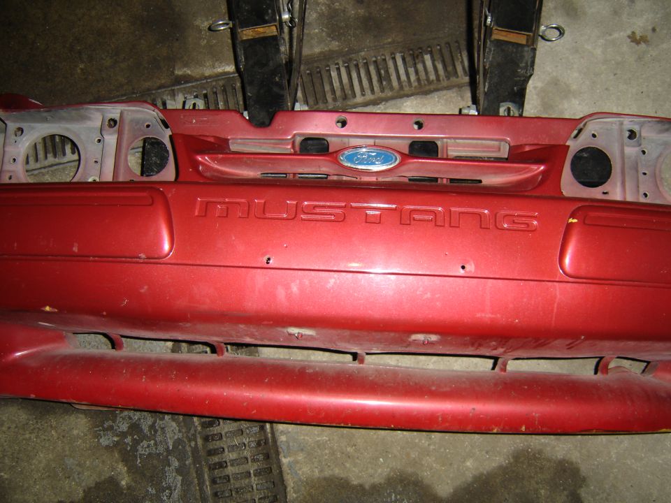 Red Ford Mustang front bumper with embossed text and Ford emblem