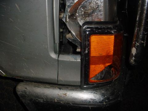 1991 Ford Bronco - The front corner of a vehicle shows a broken turn signal assembly and exposed headlight components.