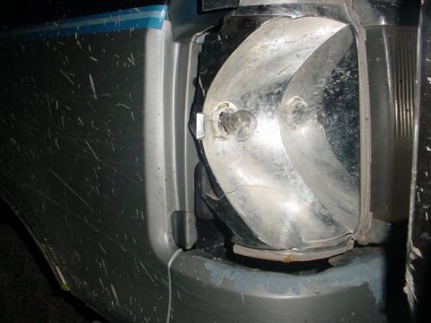 1991 Ford Bronco - Close-up of a damaged SUV taillight assembly, showing a broken bulb socket and visible scratches on the body panel.
