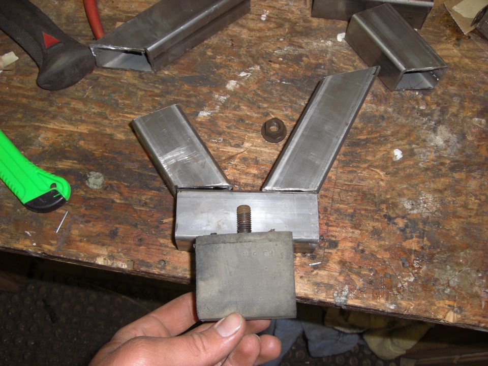 Metal bracket assembly with rubber block and bolt on a wooden workbench