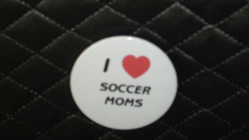 I LOVE SOCCER MOMS pin on a black quilted surface