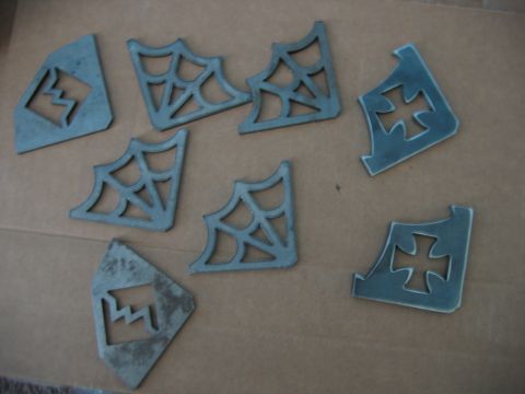 1992 Ford Mustang - A collection of metal cutouts with decorative designs, including spiderwebs and crosses, are laid out on a brown surface.