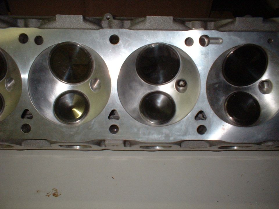 Machined V8 cylinder head deck showing polished combustion chambers with valves installed