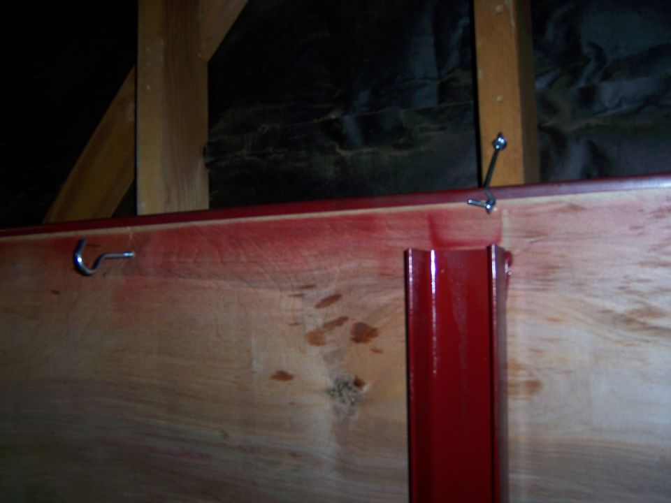 Close-up of a plywood and red-steel panel hung on garage wall hooks