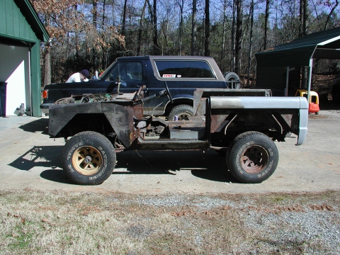 1967 Ford Bronco - A dark SUV is partially disassembled in front of a black Bronco.