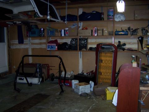 1991 Ford Bronco - A cluttered garage scene with various automotive parts and storage shelves visible on shelves and the floor.