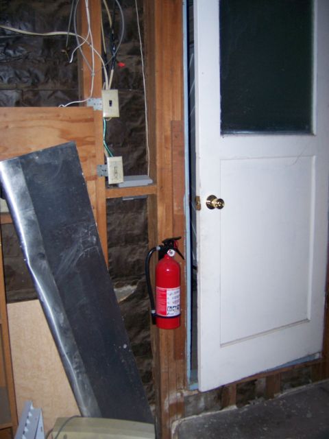 1991 Ford Bronco - A fire extinguisher is mounted on a wooden stud wall near an open door, with electrical wiring visible.