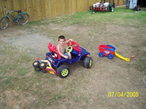 1994 Ford Bronco - A young boy enjoys a ride in his toy jeep on a sunny day in the backyard.