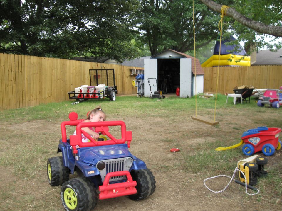 Blue toy jeep with red accents and a child inside, parked on grass