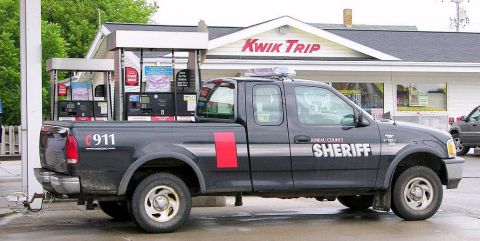 1991 Ford Crown Victoria - A sheriff's department Ford F-150 pickup truck is parked at a gas station, with "Kwik Trip" visible on the building.