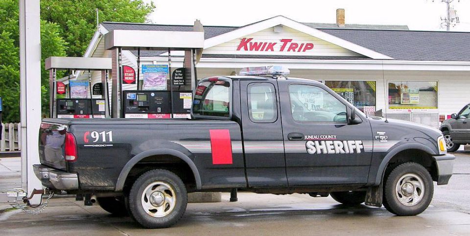 Ford F-150 pickup truck with "JUNAU COUNTY SHERIFF" markings and "911" on the tailgate, parked at a Kwik Trip gas station