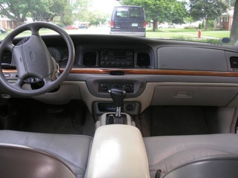 1996 Ford Crown Victoria - The dashboard and interior of a 1996 Ford Crown Victoria are visible, with a street scene outside.