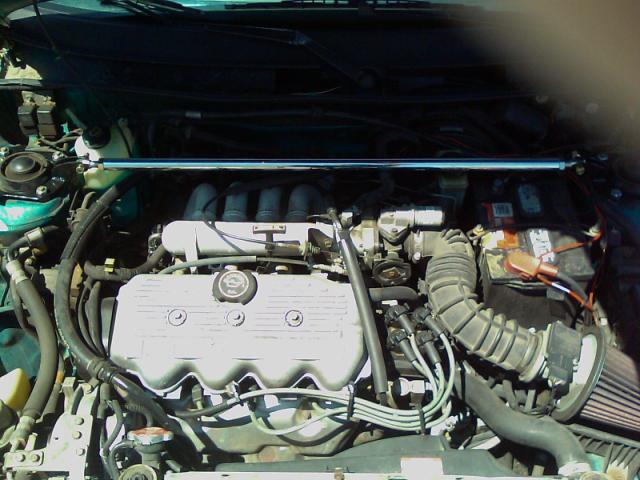 Engine bay with silver valve cover, air intake, and battery