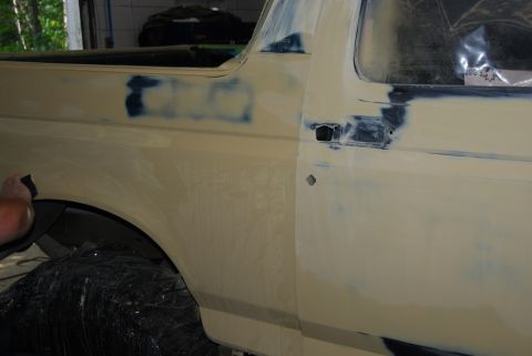 1996 Ford Bronco - A person sands the body of a vehicle, likely a Ford Bronco, as part of repair work.