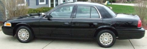 2003 Ford Crown Victoria - A black 2003 Ford Crown Victoria is parked in front of a house.