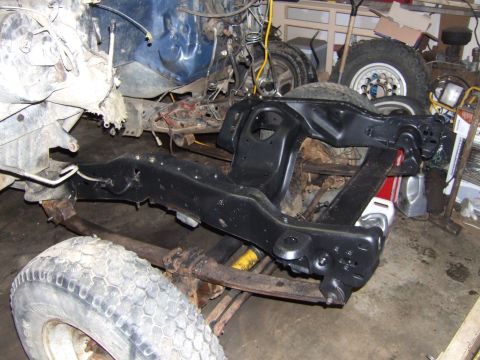 1989 Ford Bronco - A disassembled vehicle frame and suspension components are visible in a workshop setting.