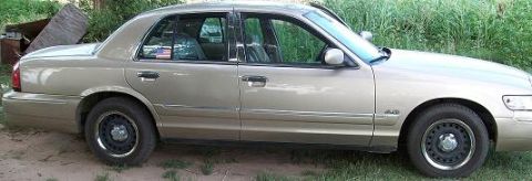 2000 Mercury Grand Marquis - A gold 2000 Mercury Grand Marquis sedan is seen from the side, parked outdoors.
