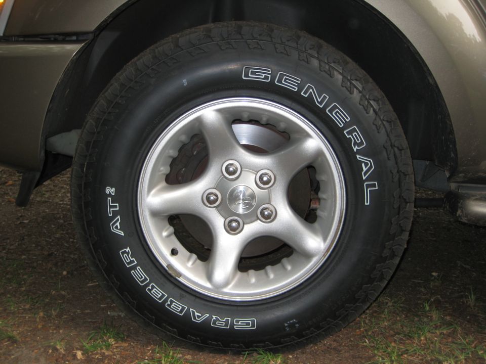 Silver five-spoke alloy wheel with General Grabber AT2 tire on a tan SUV