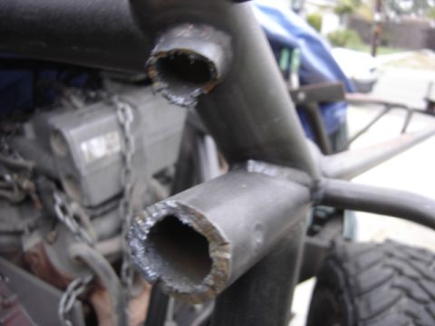 1995 Ford Bronco - Close-up of a modified vehicle's roll cage and engine components, with visible welding and rough cuts.