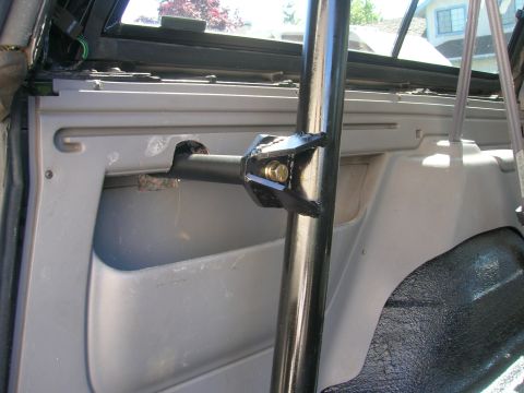 1996 Ford Bronco - Close-up of a custom roll cage mounting bracket attached to the interior panel of a vehicle.