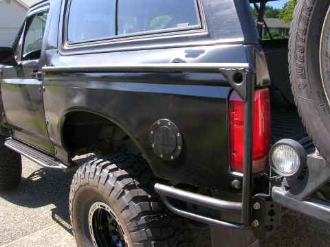 1996 Ford Bronco - Close-up of the rear passenger side of a black Ford Bronco, showing off its off-road modifications.