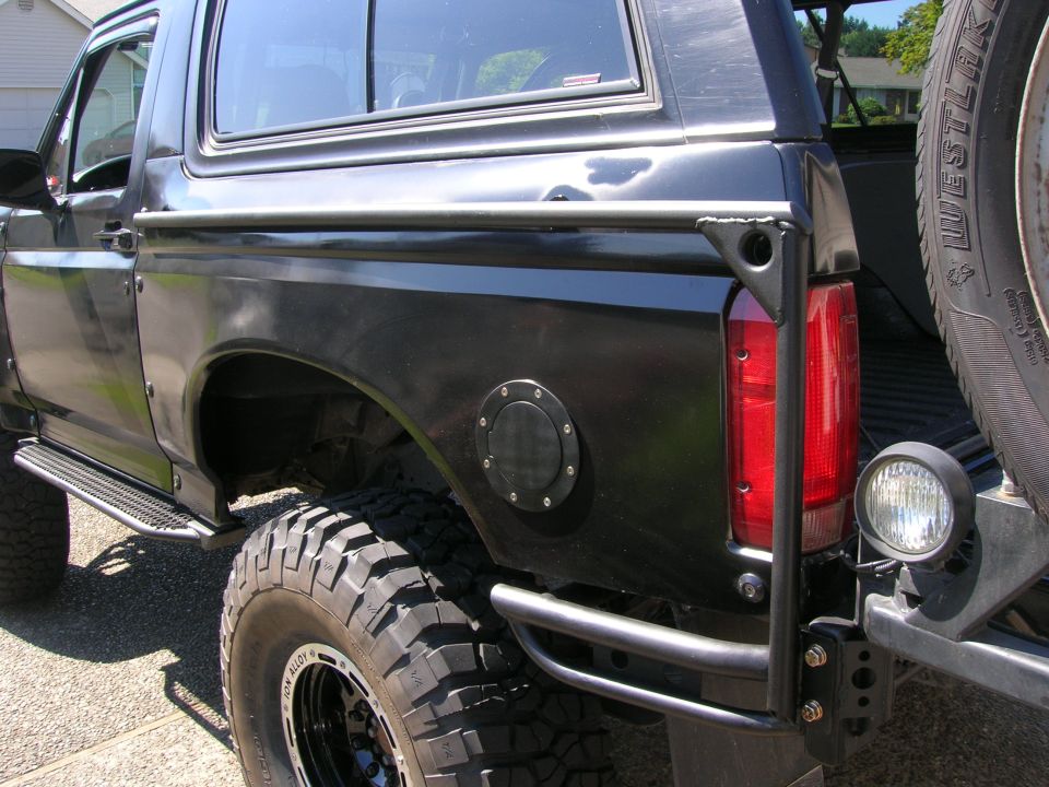 Black lifted Ford Bronco rear quarter with tube bumper and mud tires