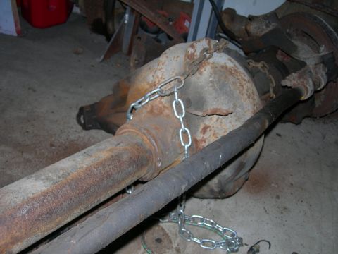 1985 Ford Bronco - A heavily rusted rear axle assembly is secured with chains, likely for transport or storage.