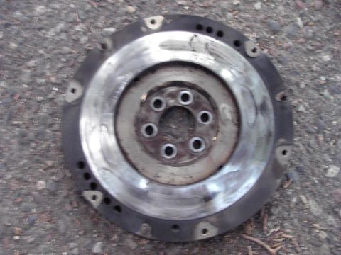 1991 Ford Probe - A metal flywheel, likely a car part, is shown resting on a gravel surface.