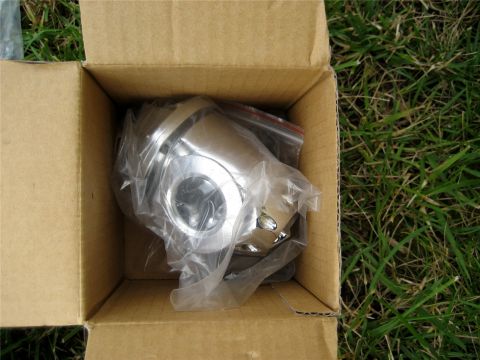 1993 Ford Probe - A shiny chrome automotive part is shown packaged in plastic within a cardboard box, resting on grass.