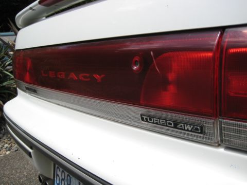 1980 Ford Bronco - Close-up of a car's rear showing the "LEGACY" and "TURBO 4WD" badging on the taillight assembly.